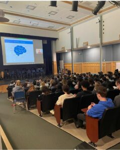 Students in an auditorium watching a presentation on a screen. 